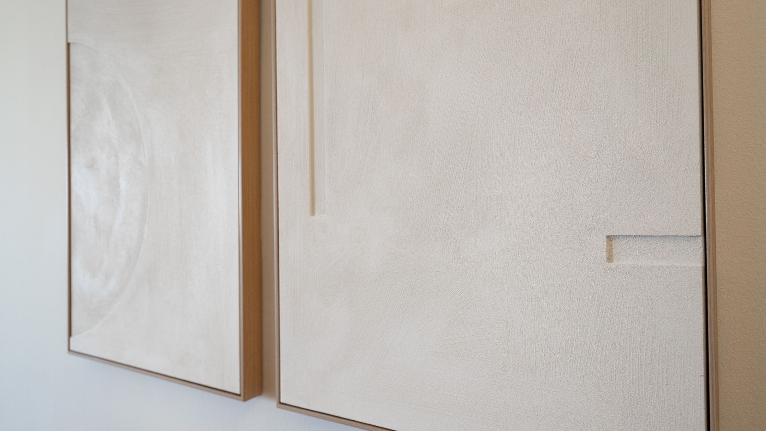 Pared blanca con un marco de puerta de madera y un pequeño rectángulo abierto.