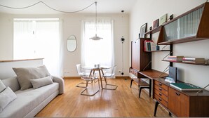 Ein modernes Wohnzimmer mit einer Couch, einem Esstisch mit Stühlen, einem Bücherregal und einem Schreibtisch mit einem Computer.