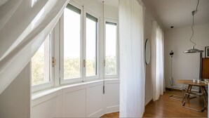 Ein Zimmer mit Erkerfenster, weißen Wänden, Holzboden, einem Esstisch mit Stühlen und einer Hängelampe.