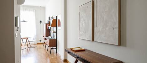 A modern interior with a wooden desk, a bookshelf, and a dining area with chairs.