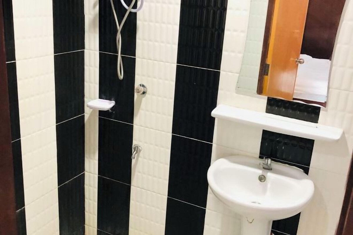 Une salle de bain avec des murs carrelés en noir et blanc, un lavabo blanc et un miroir au-dessus.