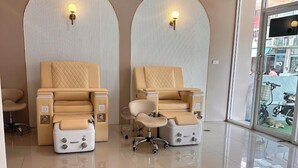 Ein Raum mit zwei Massagesesseln, einem kleinen Tisch und einer Glastür zum Außenbereich.