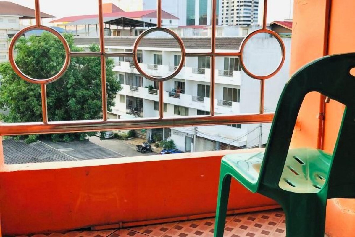 A balcony with a view of a residential building and parked vehicles.