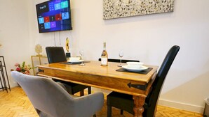 A dining area with a wooden table, two grey chairs, a bottle of wine, and a glass on the table.