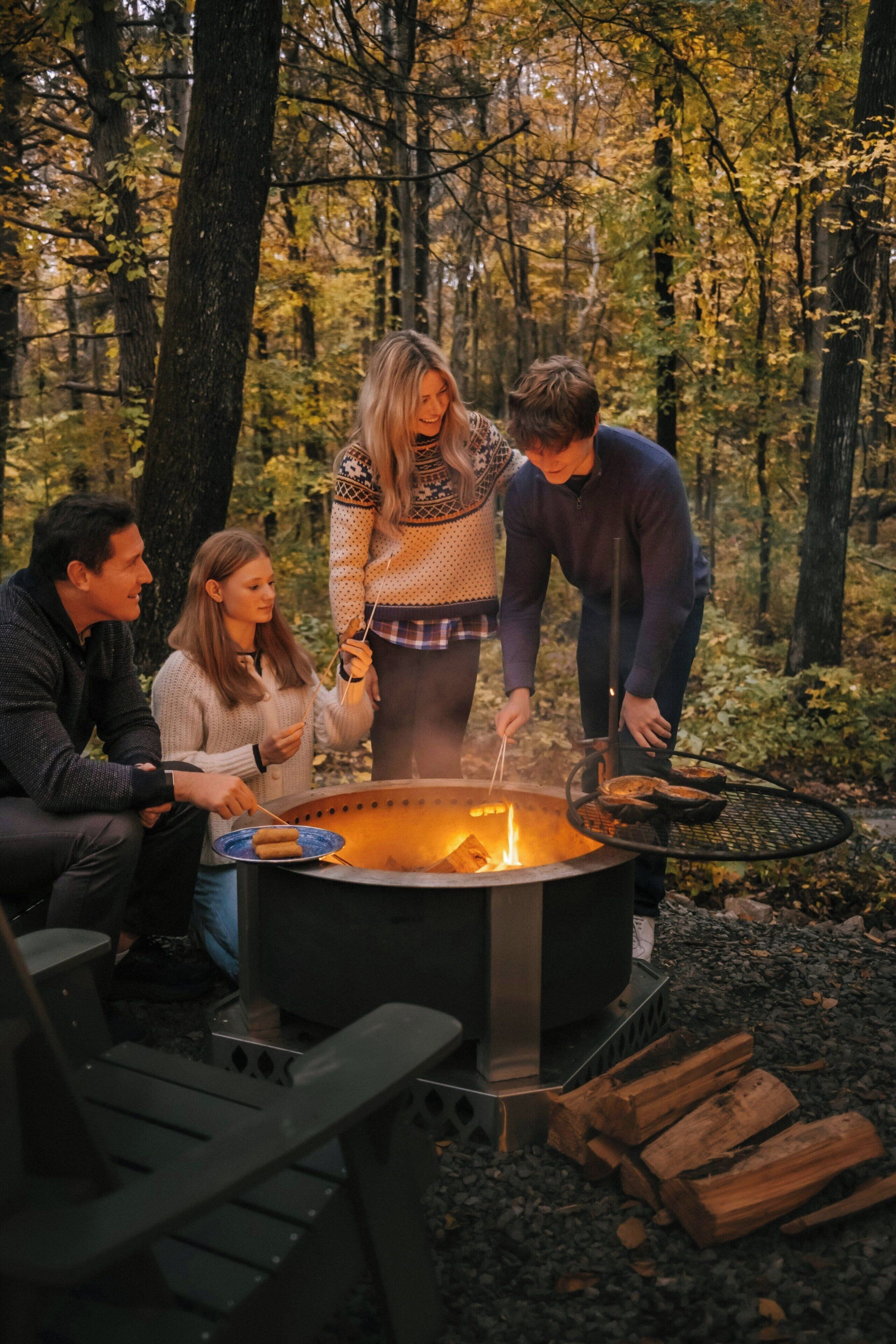 A group of people gathered around a campfire in a forest setting.