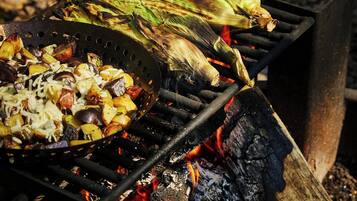 A grill with vegetables and corn on a fire.