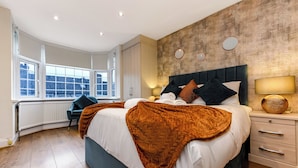 A modern bedroom with a large bed, a view of the city, and a wooden floor. - Luxurious Pad in an Unbeatable Wembley Location (Wembley)