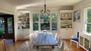 A dining area with a wooden table and white chairs, surrounded by white cabinets and shelves. - La Stella - An Oasis in the City for large groups (Seattle)
