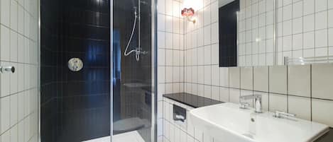 A modern bathroom with a glass-enclosed shower, a white toilet, a sink, and a mirror.