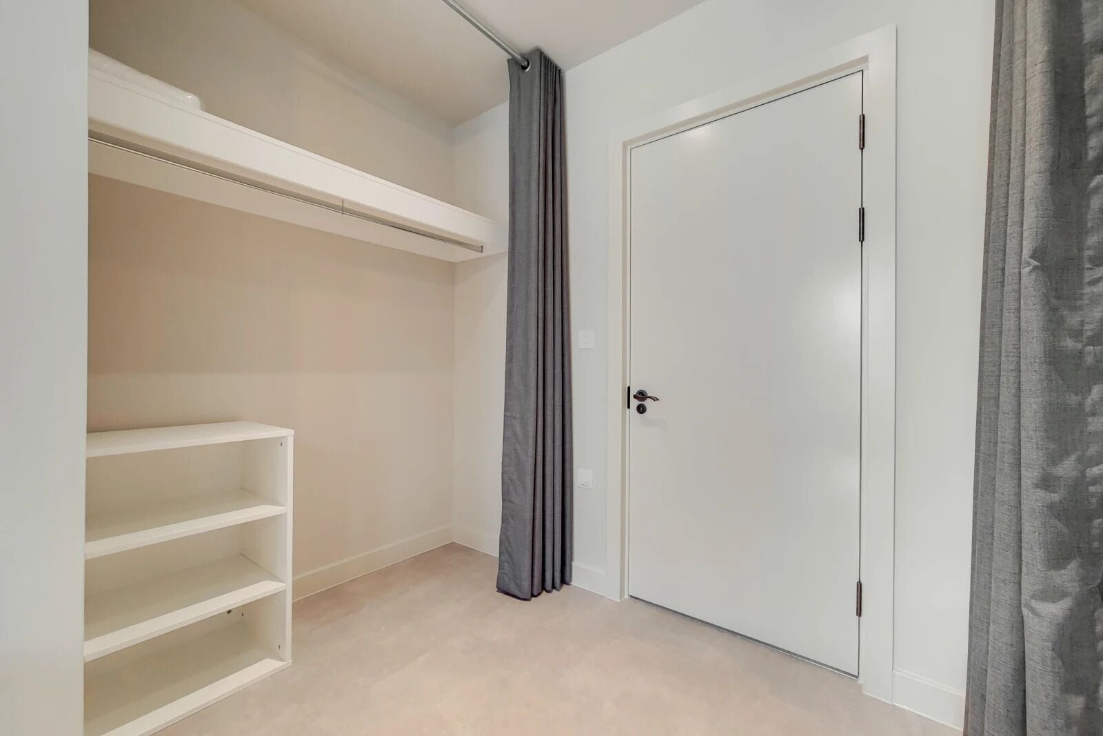 Un vestidor con estantes blancos y puerta cerrada.