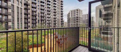 A balcony with a view of high-rise residential buildings and a landscaped area with a pathway and greenery.