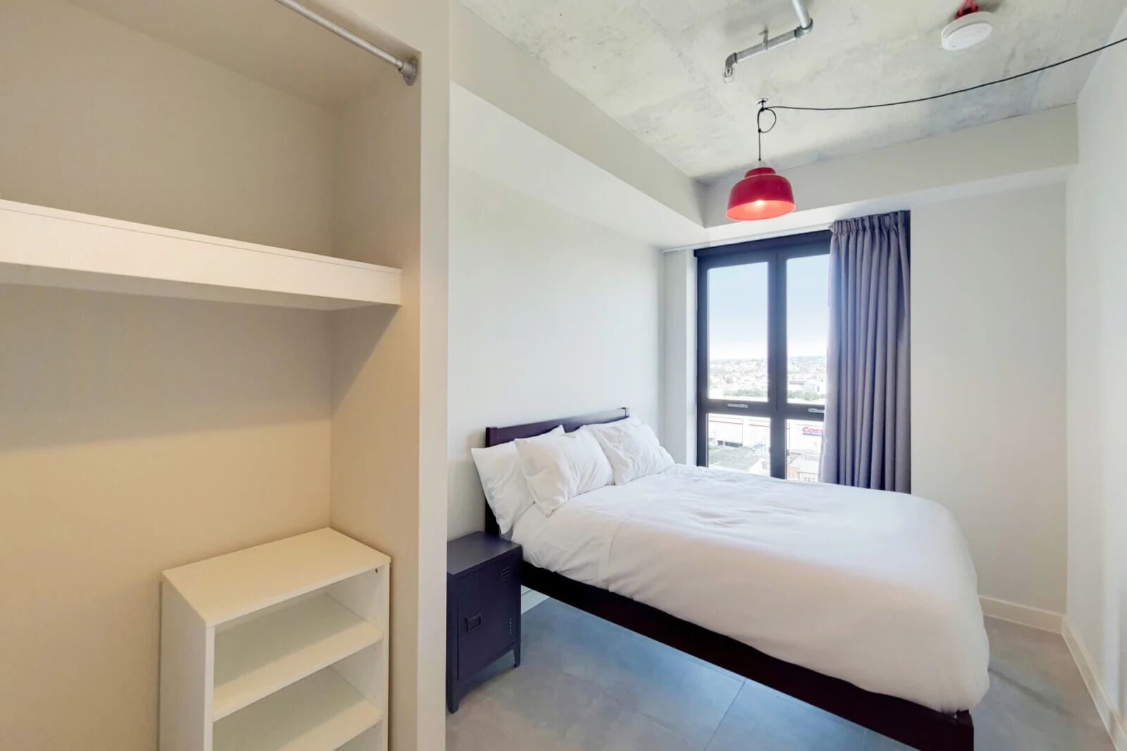 A bedroom with a bed, a wardrobe, and a window with curtains.