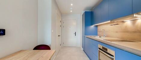 A modern kitchen with blue cabinets, a wooden countertop, and a built-in oven.