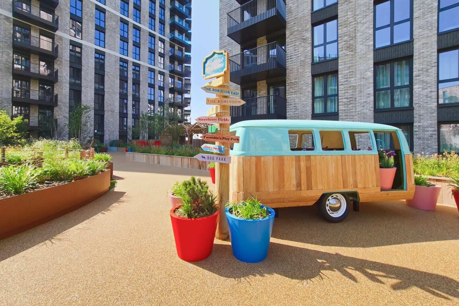 A van parked in front of a building with multiple signs pointing to amenities like 'The Robinson East' and 'Dog Park'.