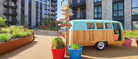 A van parked in front of a building with multiple signs pointing to amenities like 'The Robinson East' and 'Dog Park'.