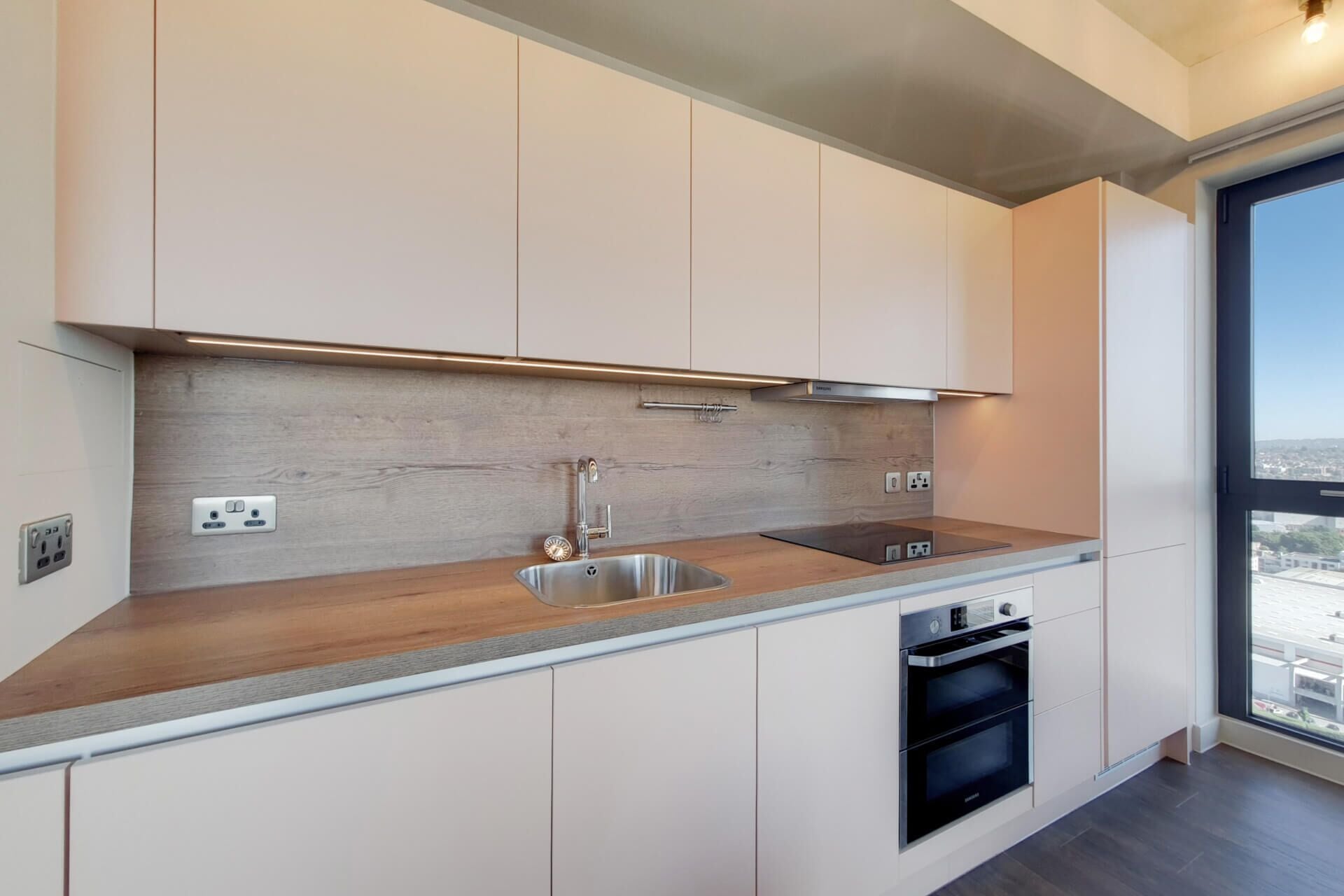 A modern kitchen with a stainless steel sink, double oven, and wooden countertop.