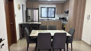 Une cuisine moderne équipée d’un réfrigérateur, d’un four à micro-ondes et d’un four encastrés. Un coin repas avec une table et des chaises est également disponible.