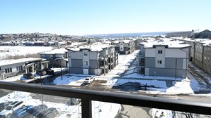 A residential area with multi-story buildings, a parking lot with several cars, and a clear sky. - New condo w/ fantastic view at west 17 Ave (Calgary)