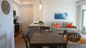 A modern kitchen with white cabinets, a built-in microwave, and a dining area with a wooden table and chairs. - New condo w/ fantastic view at west 17 Ave (Calgary)
