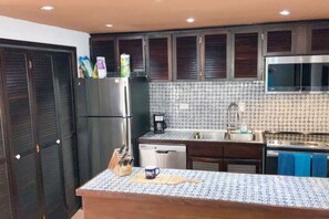 A kitchen with dark wooden cabinets, a stainless steel refrigerator, a coffee maker, and a tiled backsplash. - Rio Grande Rio Mar cluster 2,Vista Del Mar- View (Río Grande)