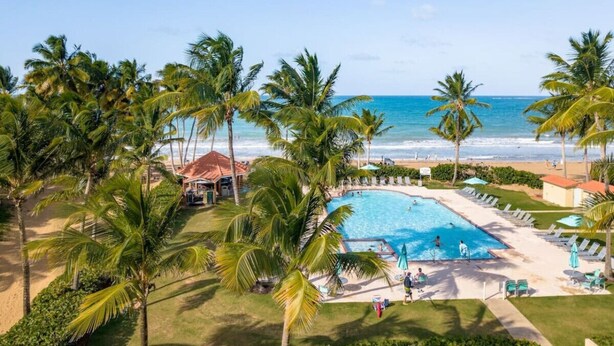 A resort with a swimming pool, palm trees, and a beach view. - Rio Grande  Rio Mar cluster 2,Vista Del Mar- View (Río Grande)