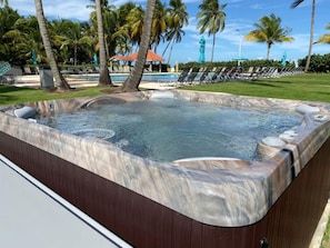 A hot tub with a marble exterior, surrounded by palm trees and a pool area. - Rio Grande Rio Mar cluster 2,Vista Del Mar- View (Río Grande)