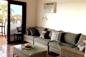 A living room with a sofa, a small table with a hat, and a balcony with a chair. - Rio Grande Rio Mar cluster 2,Vista Del Mar- View (Río Grande)