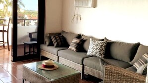 A living room with a sofa, a small table with a hat, and a balcony with a chair. - Rio Grande  Rio Mar cluster 2,Vista Del Mar- View (Río Grande)