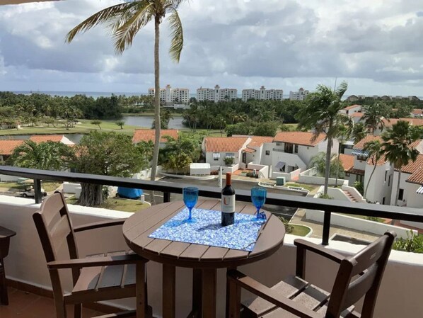 A balcony with a table, two chairs, and a bottle of wine. - Rio Grande Rio Mar cluster 2,Vista Del Mar- View (Río Grande)