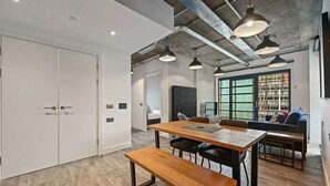 A modern kitchen with a wooden table, black chairs, and pendant lighting.