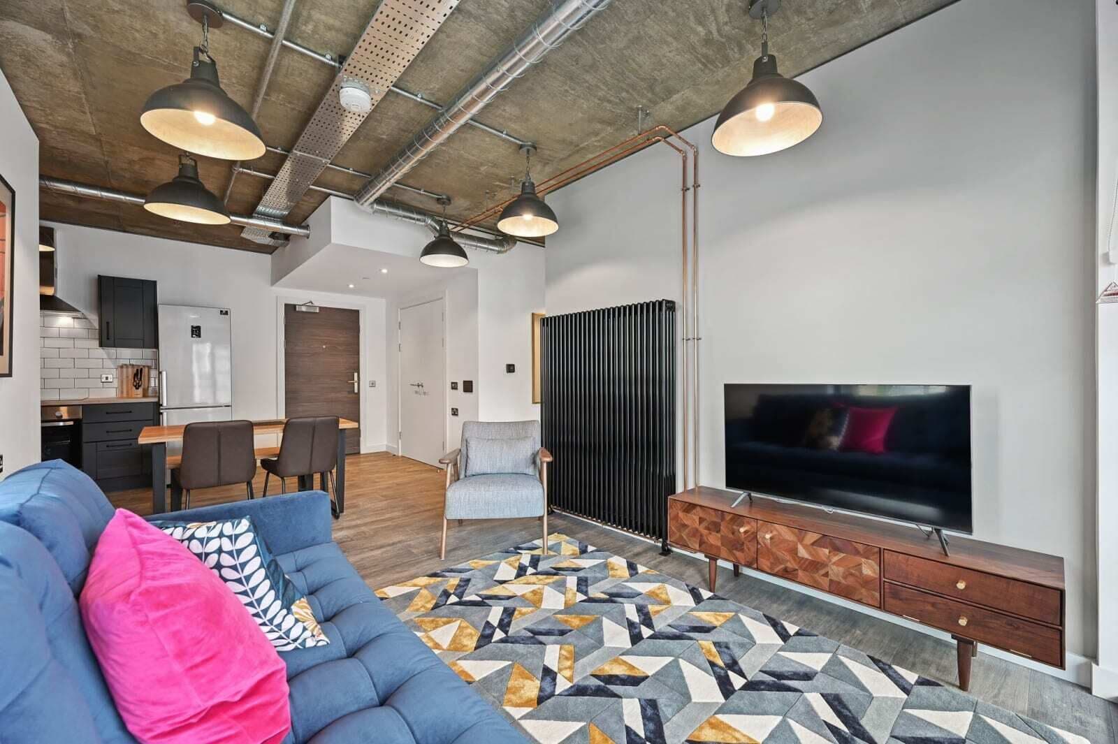 A modern living room with a sofa, TV, and patterned rug.