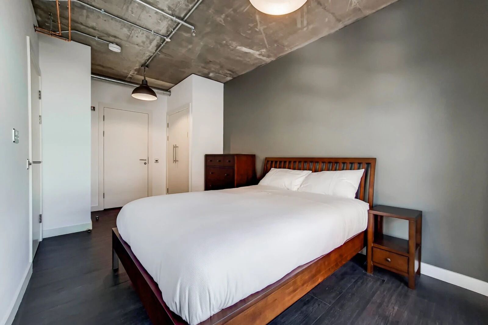 A bedroom with a wooden bed, a nightstand, and a wardrobe.