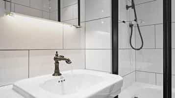 A modern bathroom with a white sink, a shower with a handheld showerhead, and a mirror above the sink.