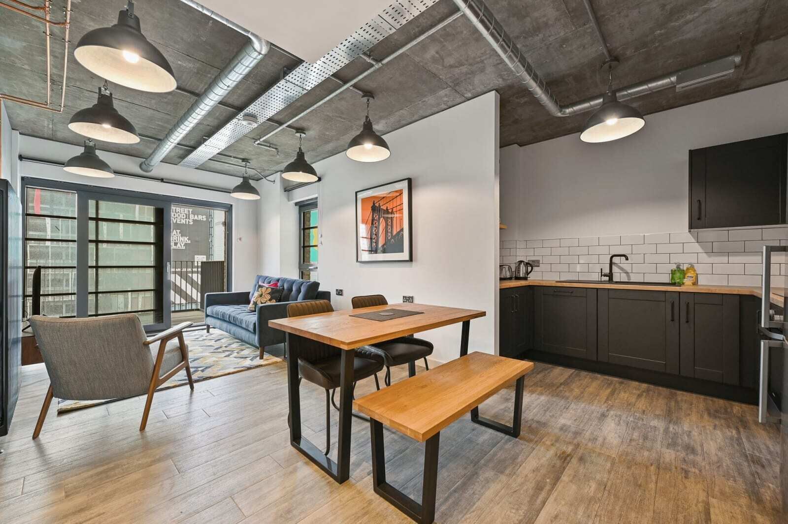A modern kitchen with dark cabinets, a wooden countertop, and a stainless steel sink.