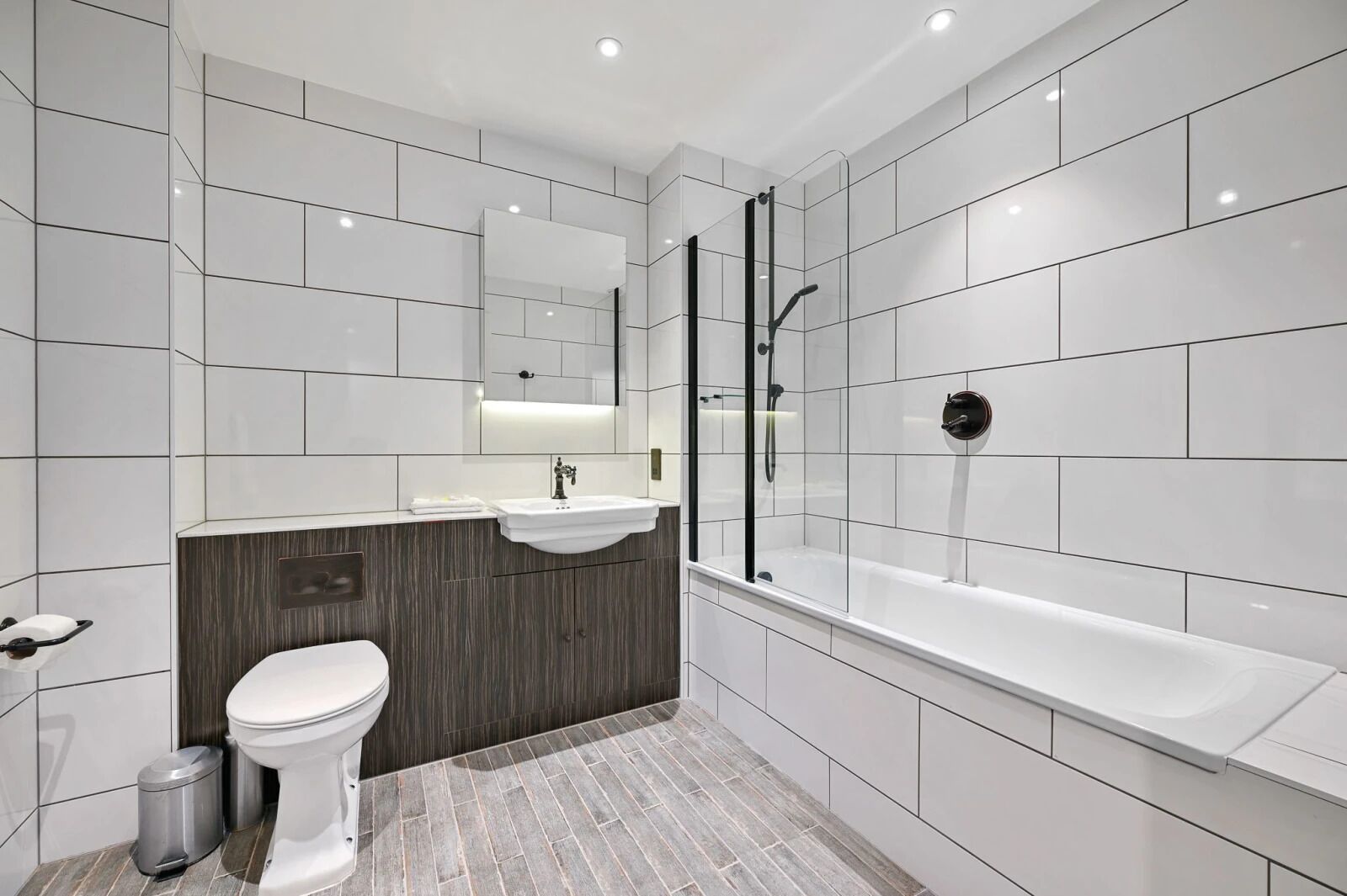 Un bagno moderno con lavandino, water e vasca da bagno bianchi.