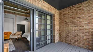 A modern room with a large sliding glass door leading to a balcony, a bed, a yellow armchair, and a radiator.