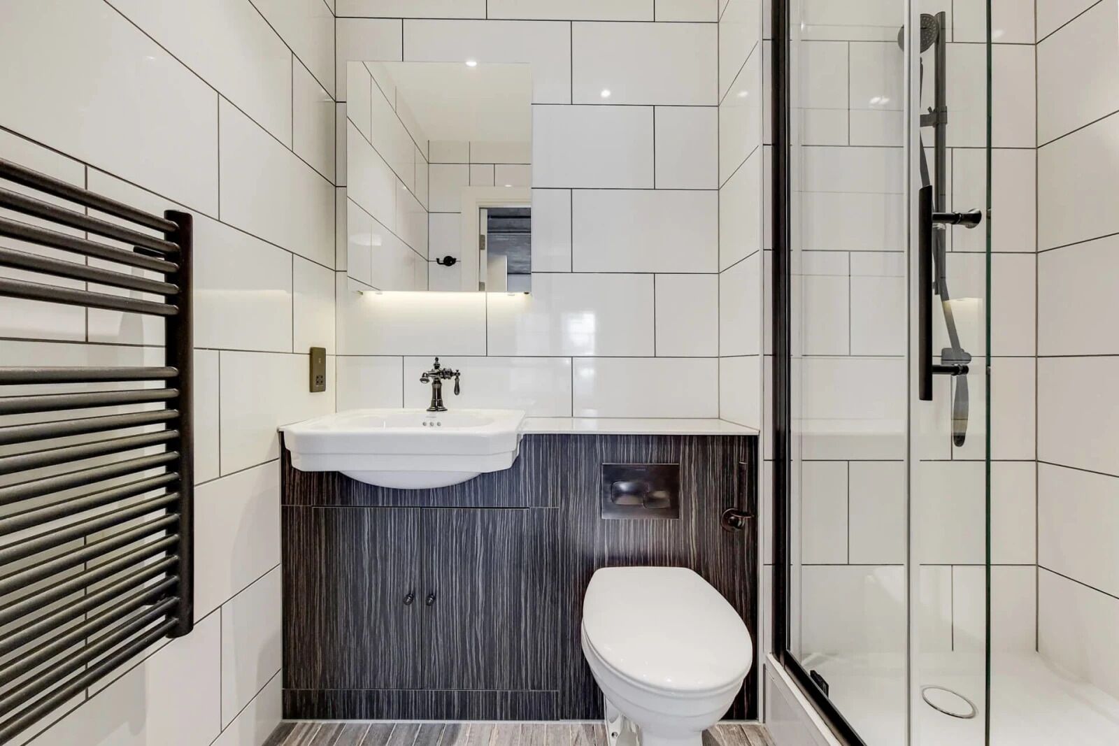 A modern bathroom with a white sink, dark wood vanity, and a toilet.