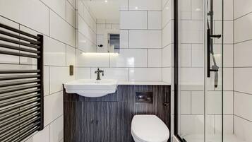 A modern bathroom with a white sink, dark wood vanity, and a toilet.