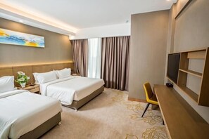Ein Hotelzimmer mit zwei Betten, einem Schreibtisch, einem Fernseher und einem großen Fenster mit Vorhängen.