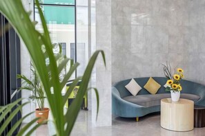 Un intérieur moderne avec un canapé bleu aux lignes courbes, une table basse ronde en bois et une plante en pot.