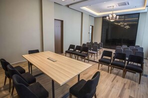 Une salle de conférence avec une longue table, de nombreuses chaises et un espace aménagé en scène.