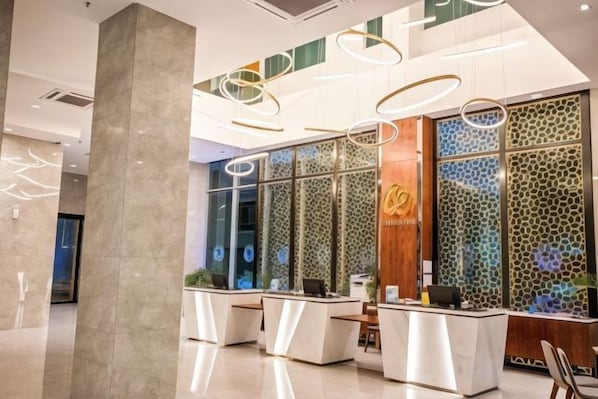 A hotel reception area with a modern design, featuring a reception desk, seating area, and decorative wall panels.