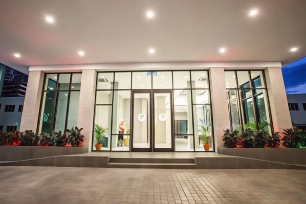 A modern building with large glass doors, a tiled entrance area, and potted plants. - Grand Flora Hotel (Melaka)