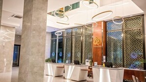 A modern reception area with a marble floor, glass partitions, and a wooden reception desk. - Grand Flora Hotel (Melaka)