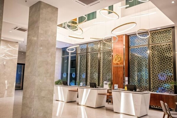 A modern reception area with a marble floor, glass partitions, and a wooden reception desk. - Grand Flora Hotel (Melaka)