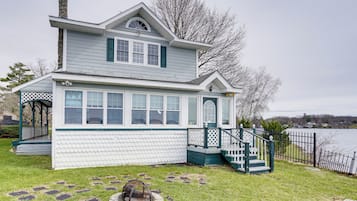 Welcome to this charming two-story house, situated by a serene lake with a well-maintained lawn and a cozy outdoor space featuring a fire pit.