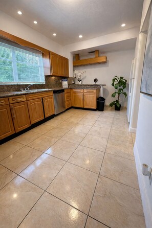 A kitchen with wooden cabinets, a granite countertop, a stainless steel sink, and a potted plant. - Safari Wynwood  (Miami)