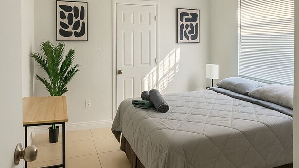 A bedroom with a bed, a bedside table, a potted plant, and artwork on the walls. - Safari Wynwood  (Miami)