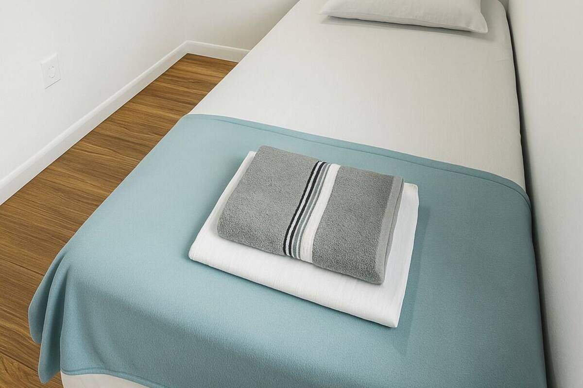 A small, single-bed room with a wooden floor and white walls.