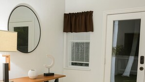 A room with a wooden table, a mirror, a window with blinds, and a door leading outside. - Safari Wynwood  (Miami)
